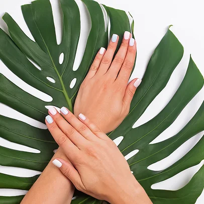 Mains manucurées avec des ongles pastel sur une grande feuille verte de Monstera à Lucé près de Chartres en Eure-et-Loir 28