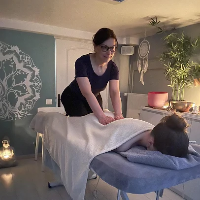 Une femme masse le dos d'une cliente allongée sur une table.